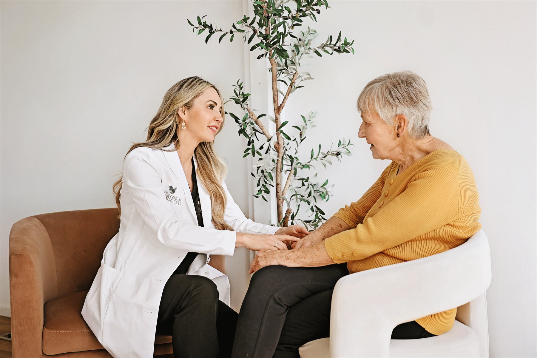 A Juniper Dermatology dermatologist holding a patient's hands during a warm, reassuring psoriasis consultation in Bend, Oregon