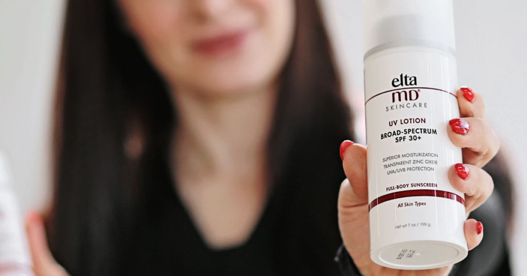 Woman holding a bottle of elta md brand sunscreen.